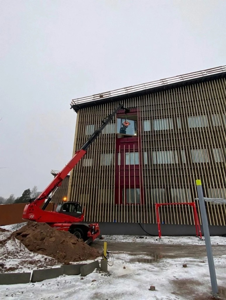 Kurottaja nostaa ikkunaa puuritiläjulkisivuun talvityömaalla